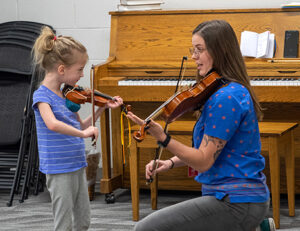 child and teacher with violins